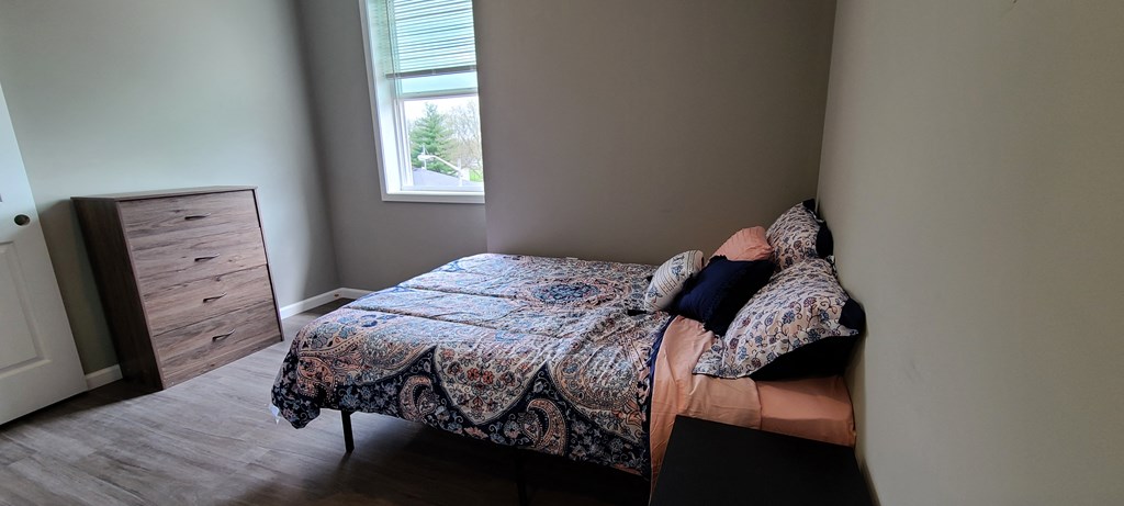 a bedroom with a bed and a dresser and a window