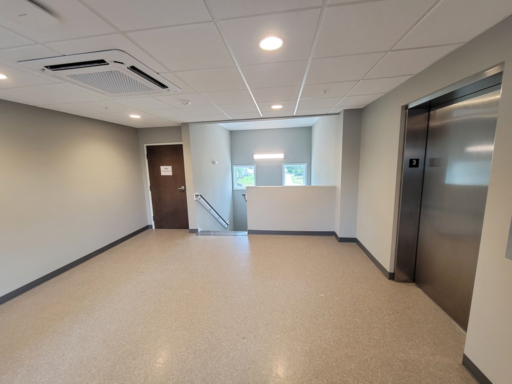 an empty room in an office building with a door to a hallway