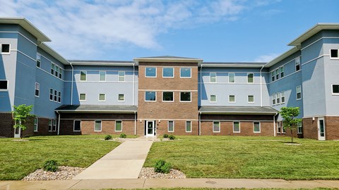 an exterior view of an apartment building with a green lawn