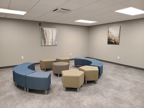 a waiting room with blue couches and chairs and two paintings on the wall