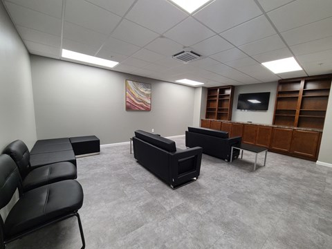 an empty waiting room with couches and a television