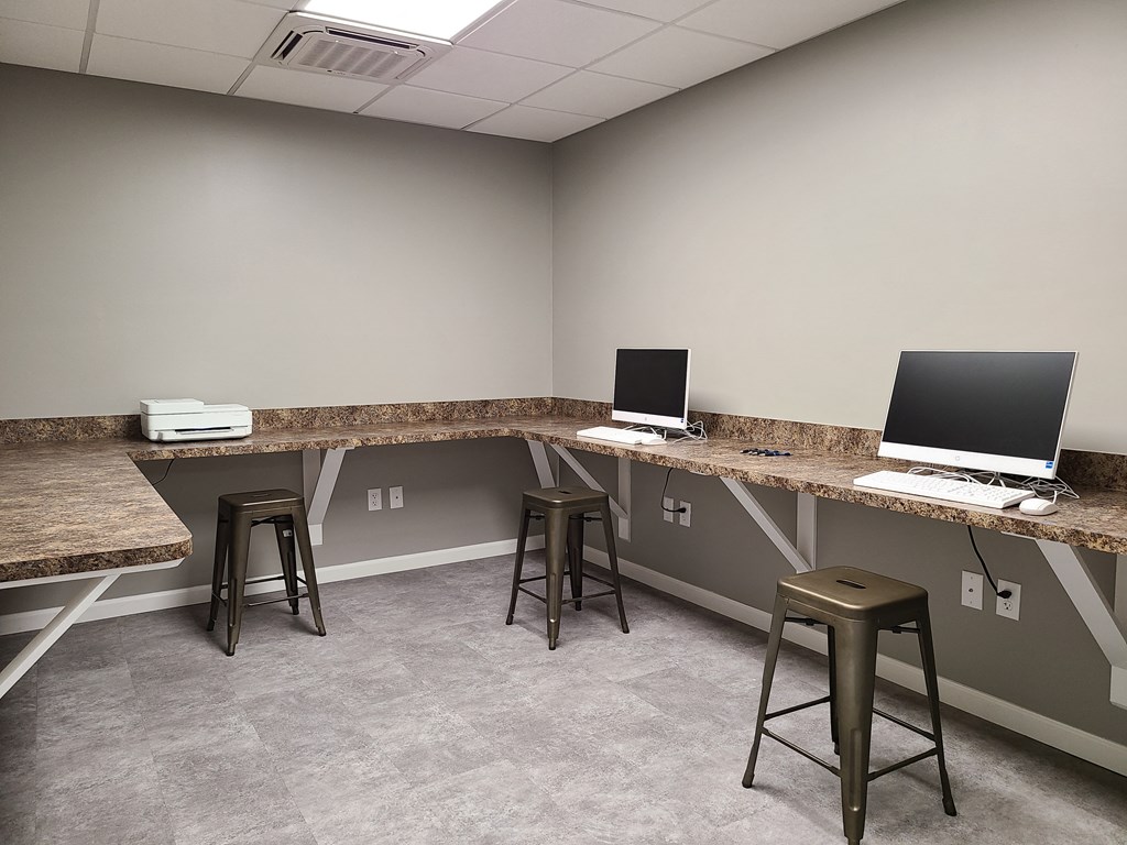 a room with two desks with computers and stools