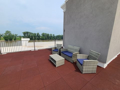 a terrace with chairs and a wall and a balcony