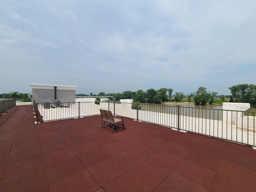 a rooftop patio with a bench and a metal fence