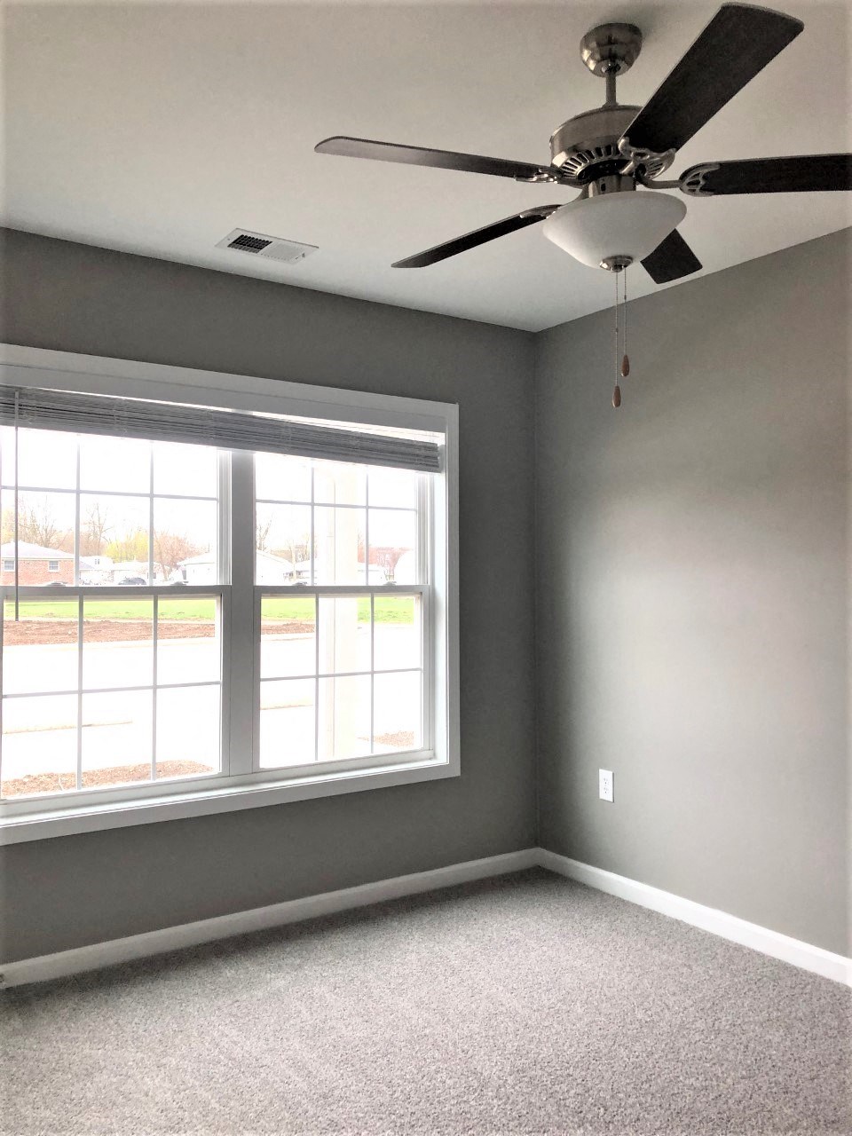 an empty room with a ceiling fan and a window