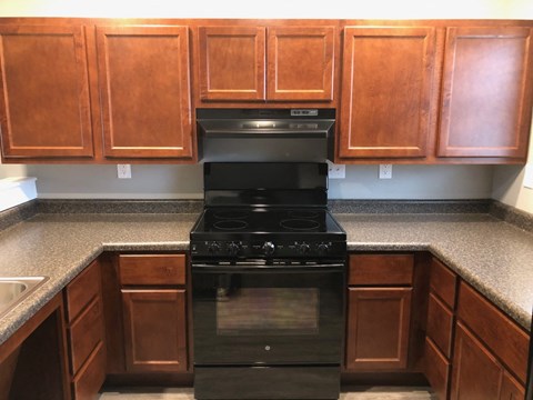 a kitchen with a stove and counters and wooden cabinets