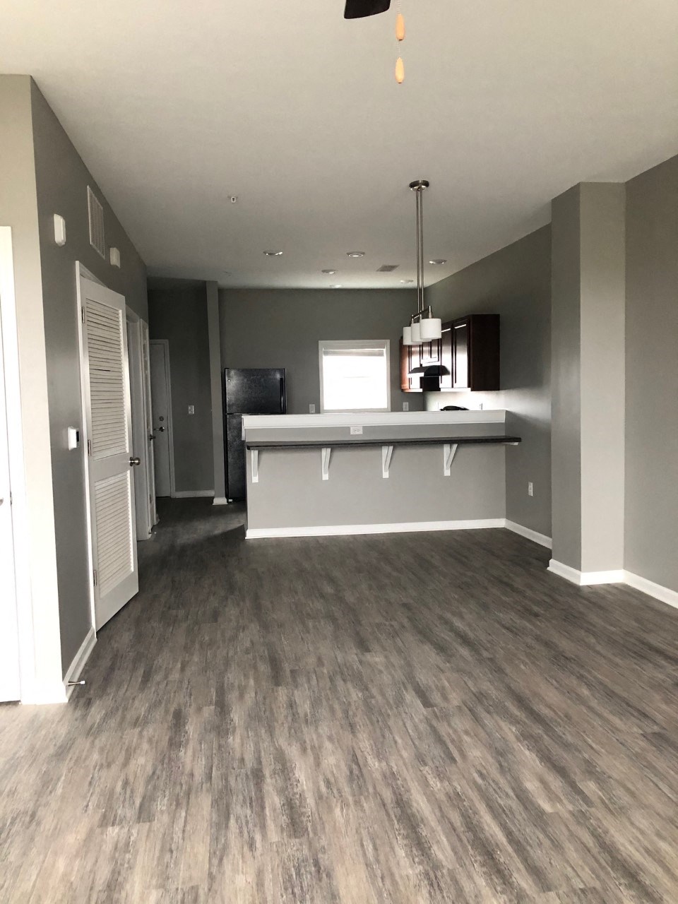 a renovated living room and kitchen with gray walls and wood floors