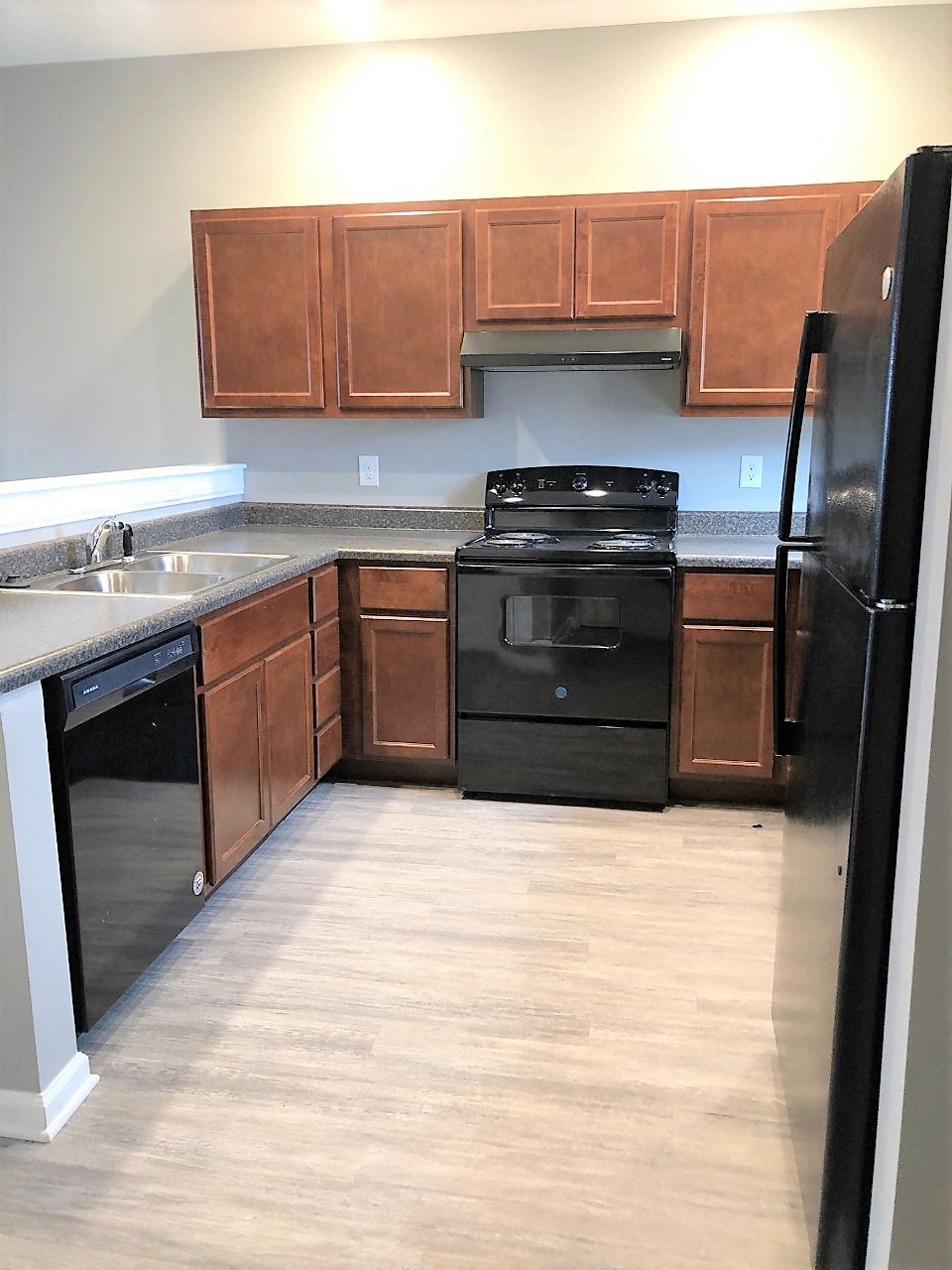 an empty kitchen with black appliances and wooden cabinets