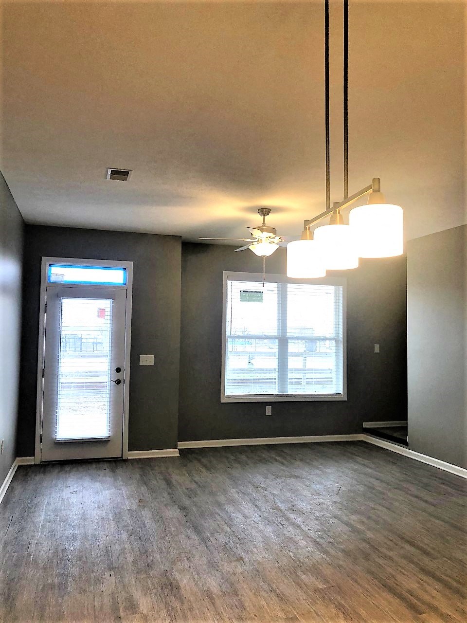 an empty living room with wood floors and a door