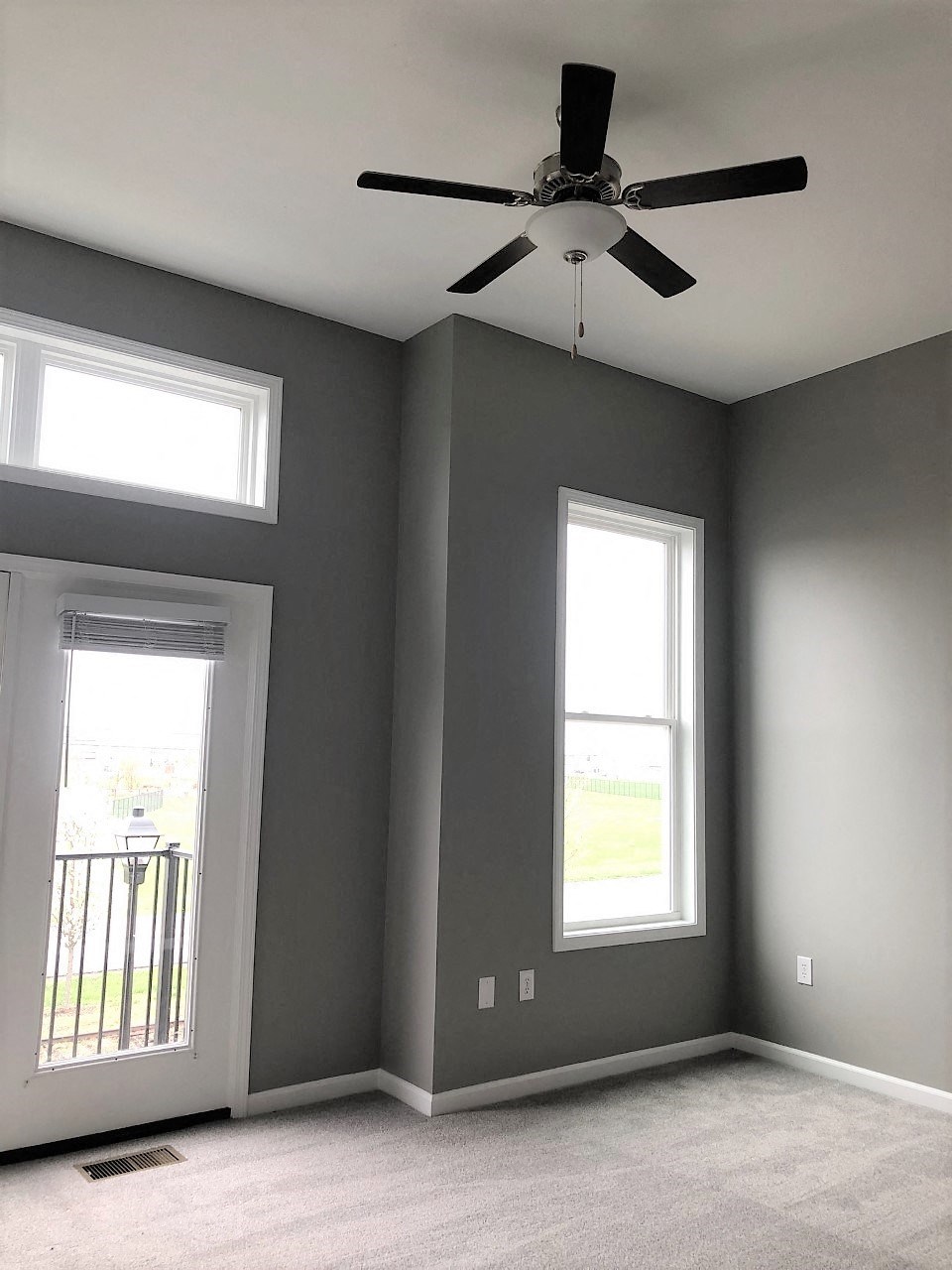 an empty room with a ceiling fan and two windows