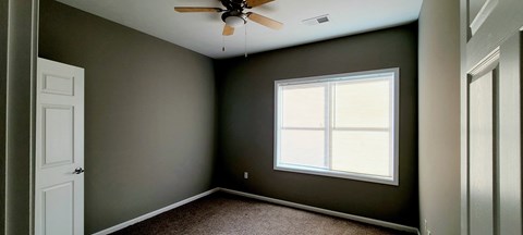 an empty room with a window and a ceiling fan
