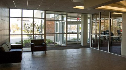 an empty lobby of a building with chairs and glass doors