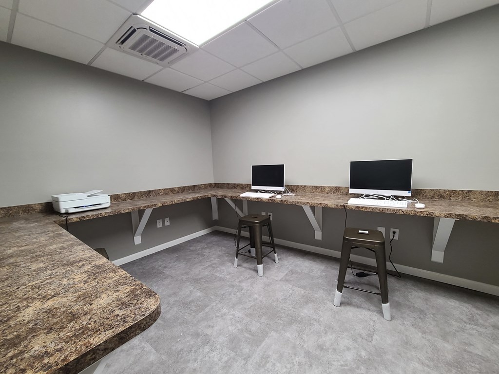 a room with two computers and a counter with two stools