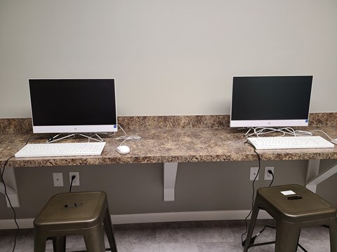 a desk with two computer monitors and two stools
