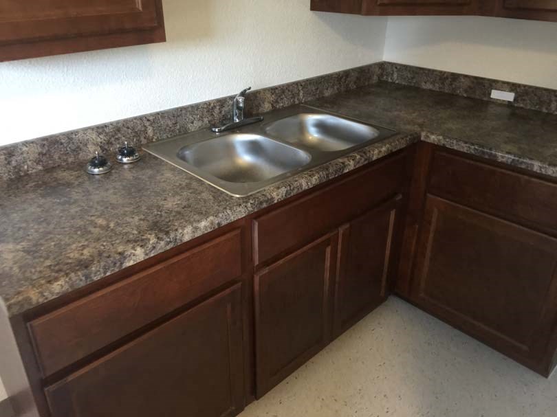 a kitchen with a stainless steel sink and wooden cabinets