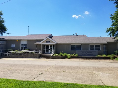 a view of the front of a gray building with stairs and a sidewalk