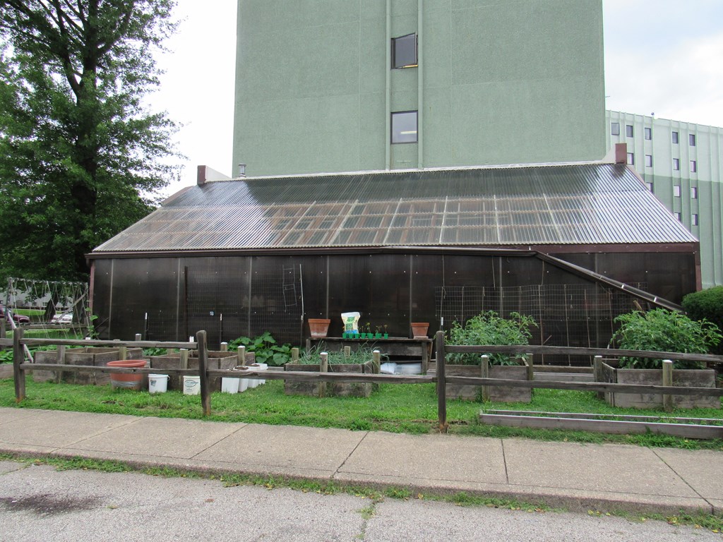 an old greenhouse with a tall building in the background