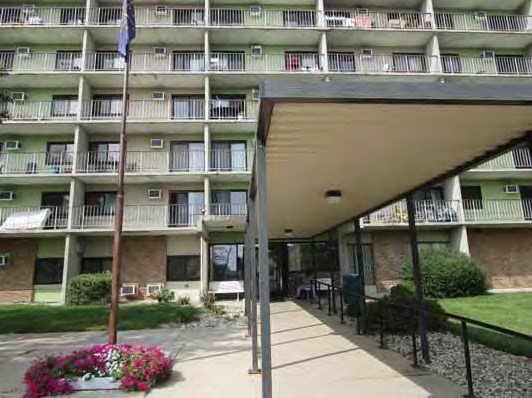 the front of an apartment building with a porch and a flag