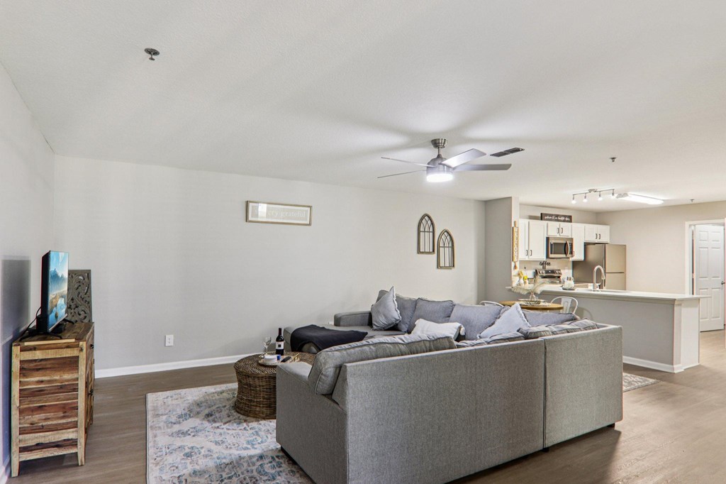 A living room with a grey couch and a ceiling fan.