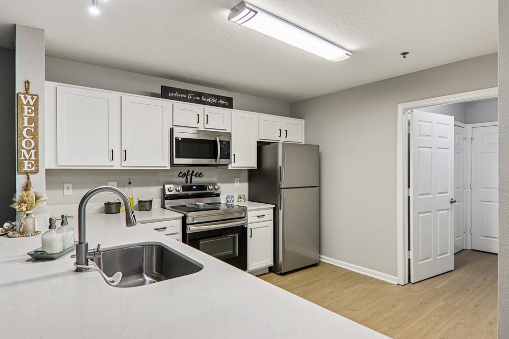 A kitchen with a sink, stove, and refrigerator.