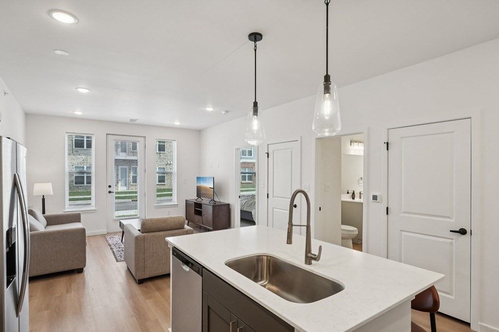 A modern kitchen with a white countertop and a stainless steel sink.