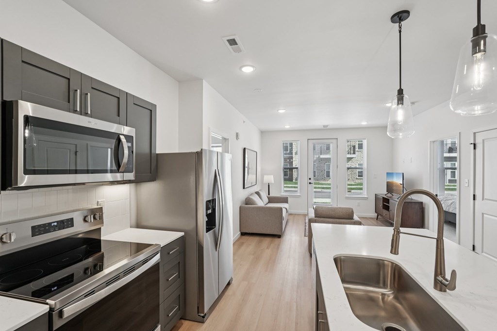 A modern kitchen with stainless steel appliances and wooden floors.