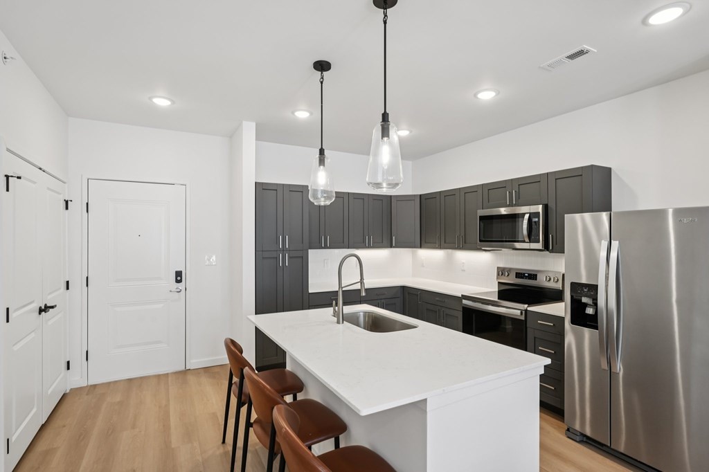 A modern kitchen with a white island and stainless steel appliances.