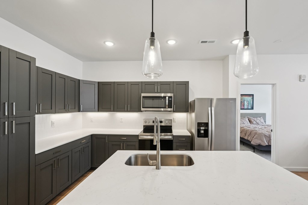 A modern kitchen with a stainless steel sink and dark brown cabinets.