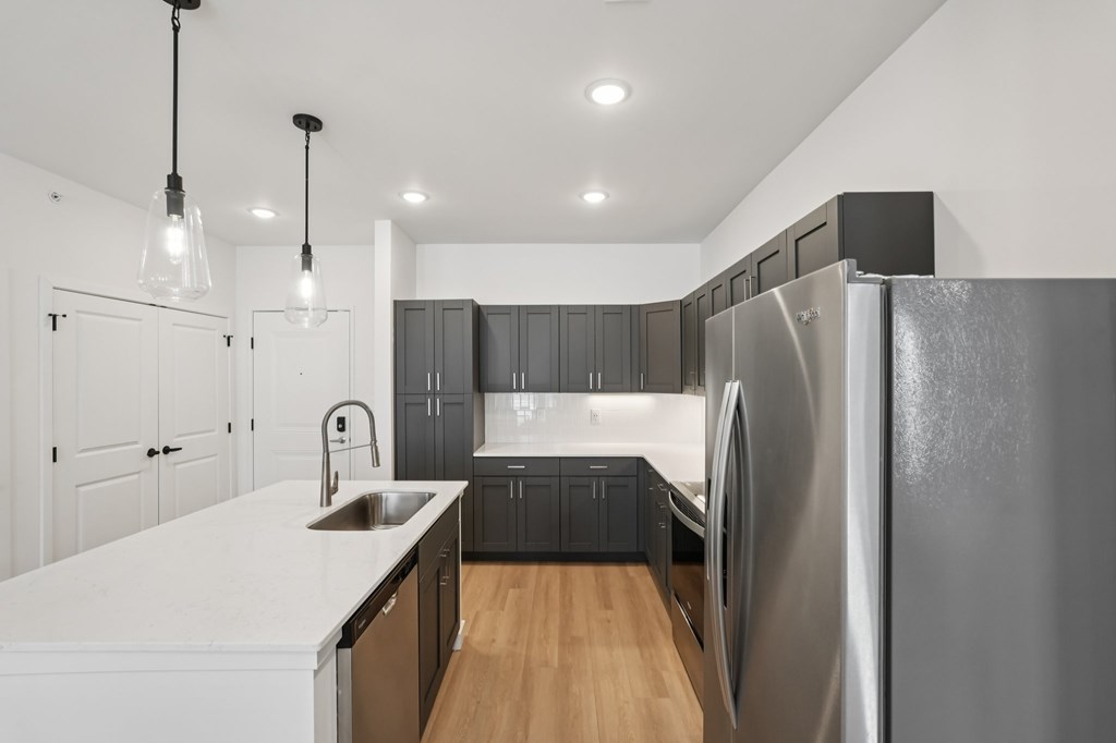 A modern kitchen with a large refrigerator and wooden floors.