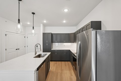 A modern kitchen with a large refrigerator and wooden floors.