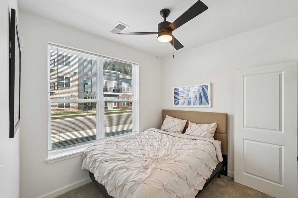 A bedroom with a large bed and a ceiling fan.