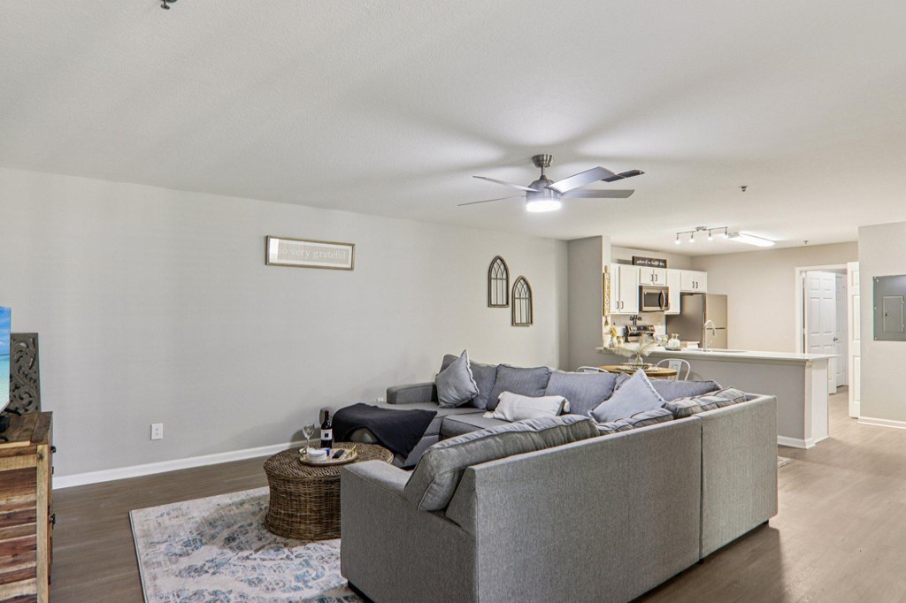A living room with a grey couch and a ceiling fan.