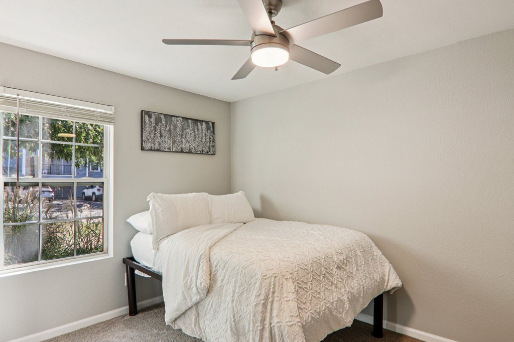 A bedroom with a bed, pillow, and a fan.