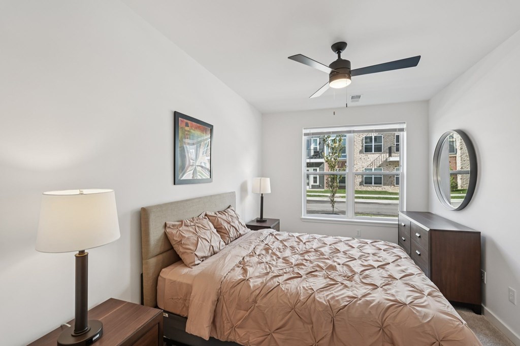 A bedroom with a bed, nightstands, and a ceiling fan.