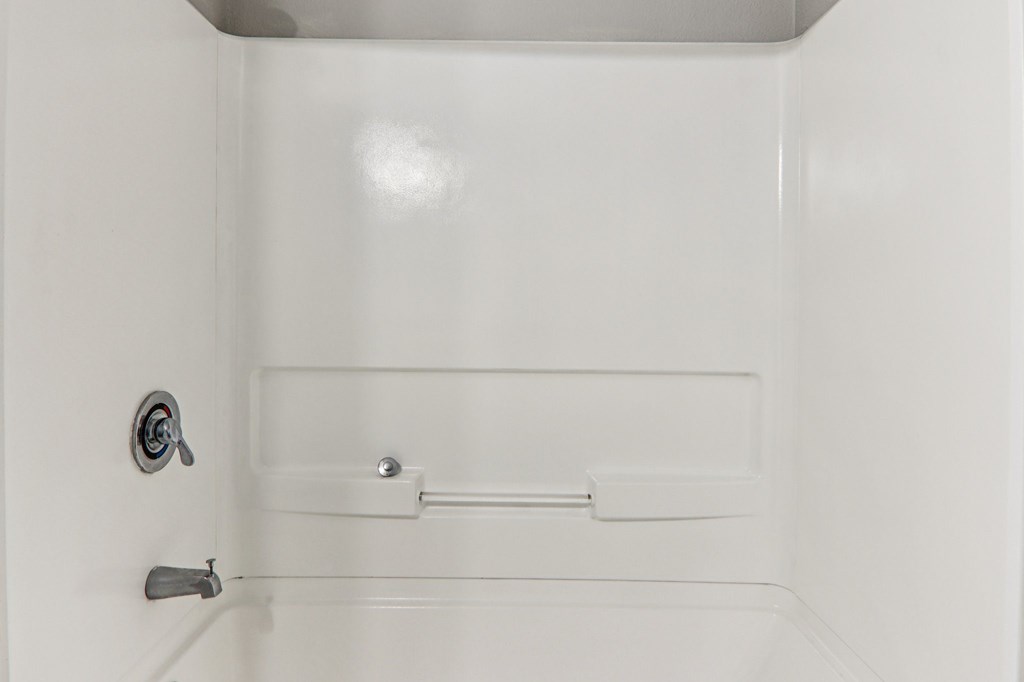 A white bathroom with a toilet and a shower.