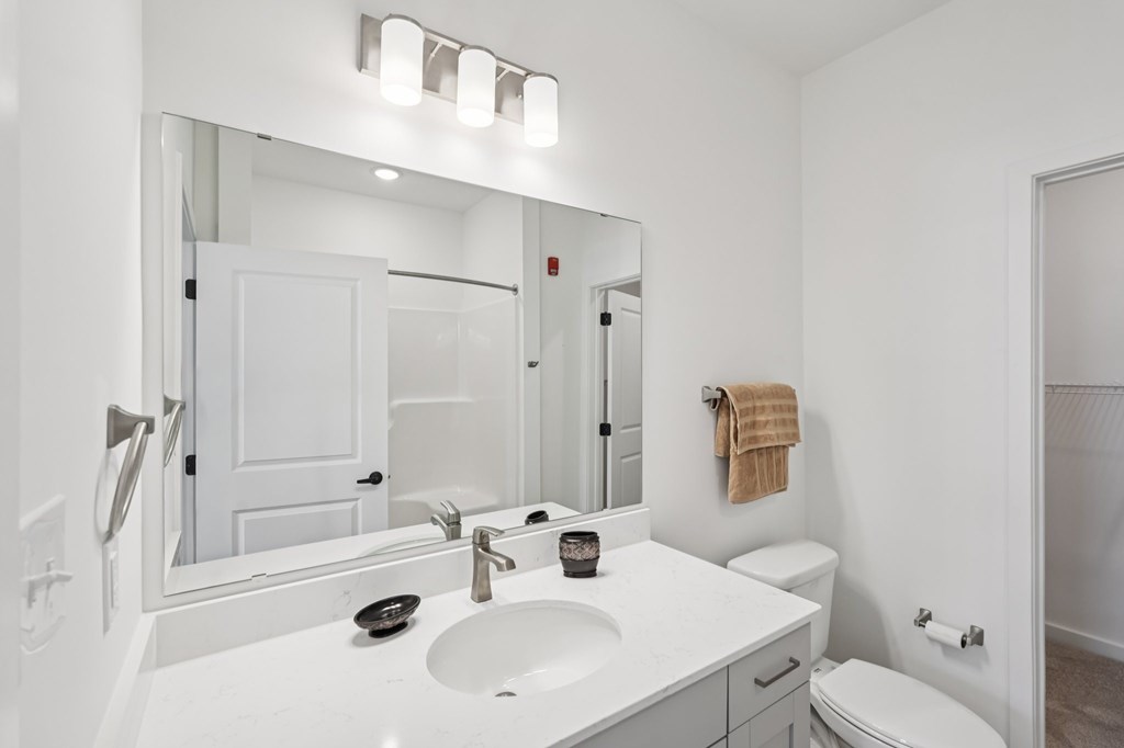 A white bathroom with a toilet, sink, and mirror.