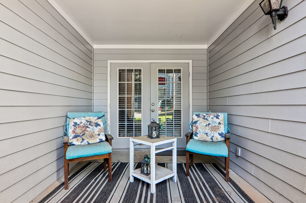 A small porch with a table and two chairs.