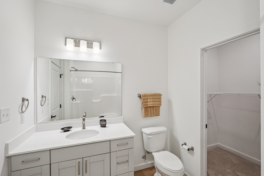 A white bathroom with a toilet, sink, and mirror.
