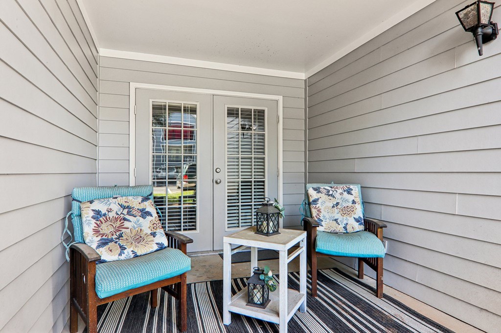 A porch with two chairs and a table.