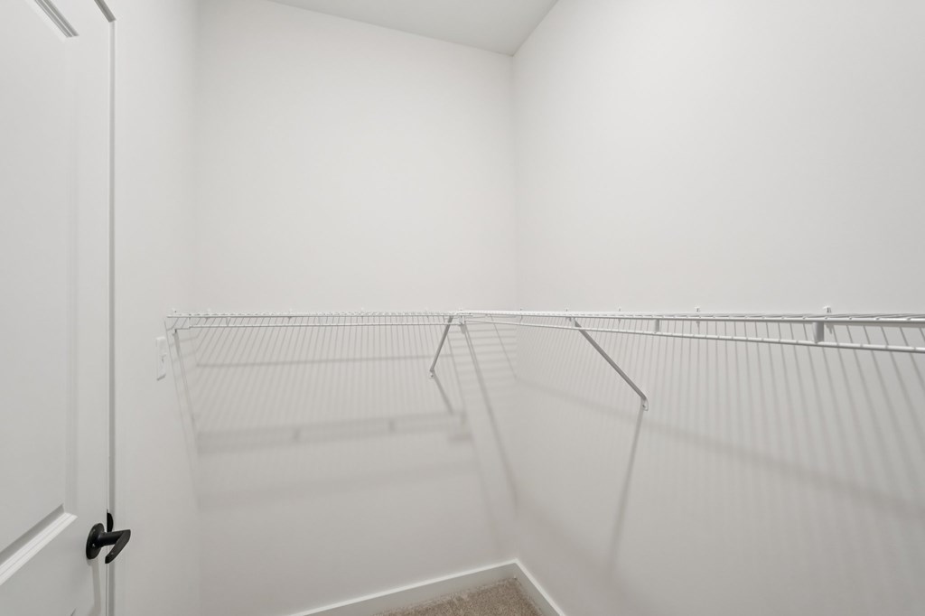 A white closet with a metal rod for hanging clothes.