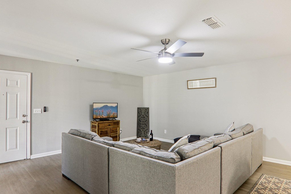 A living room with a grey couch and a ceiling fan.