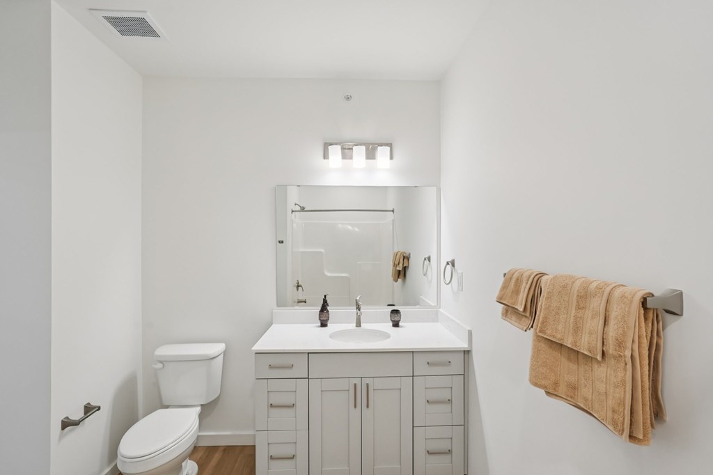 A white bathroom with a toilet, sink, and mirror.