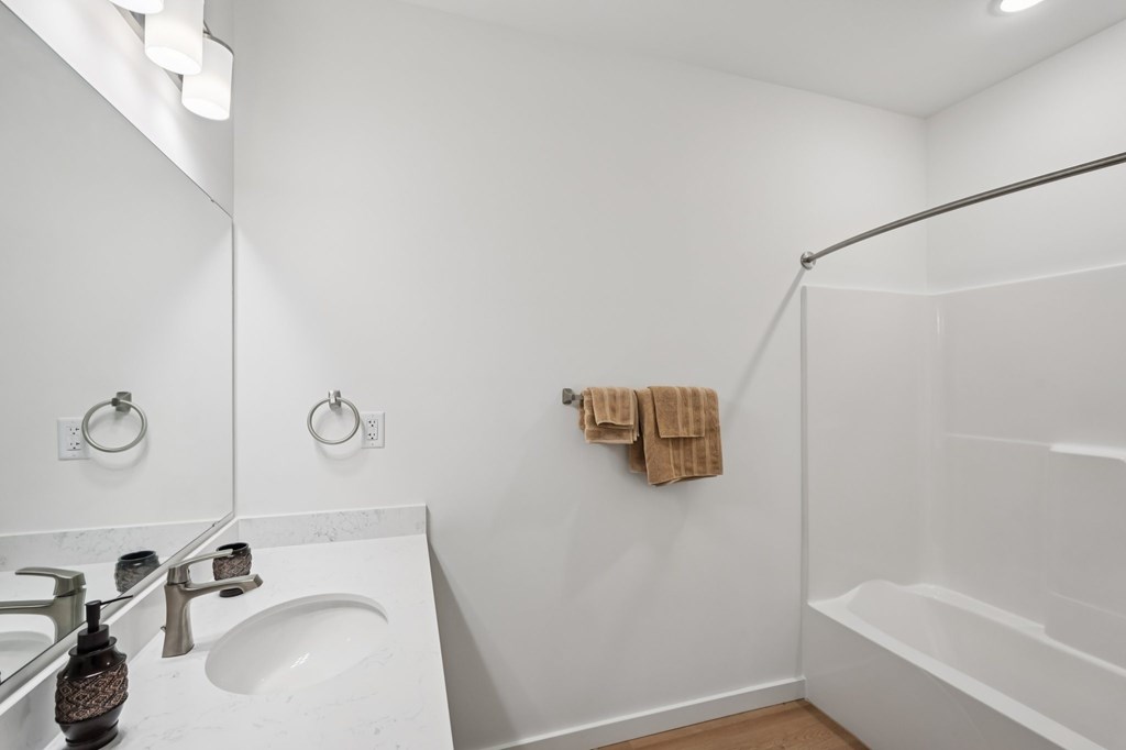 A white bathroom with a towel hanging on the wall.