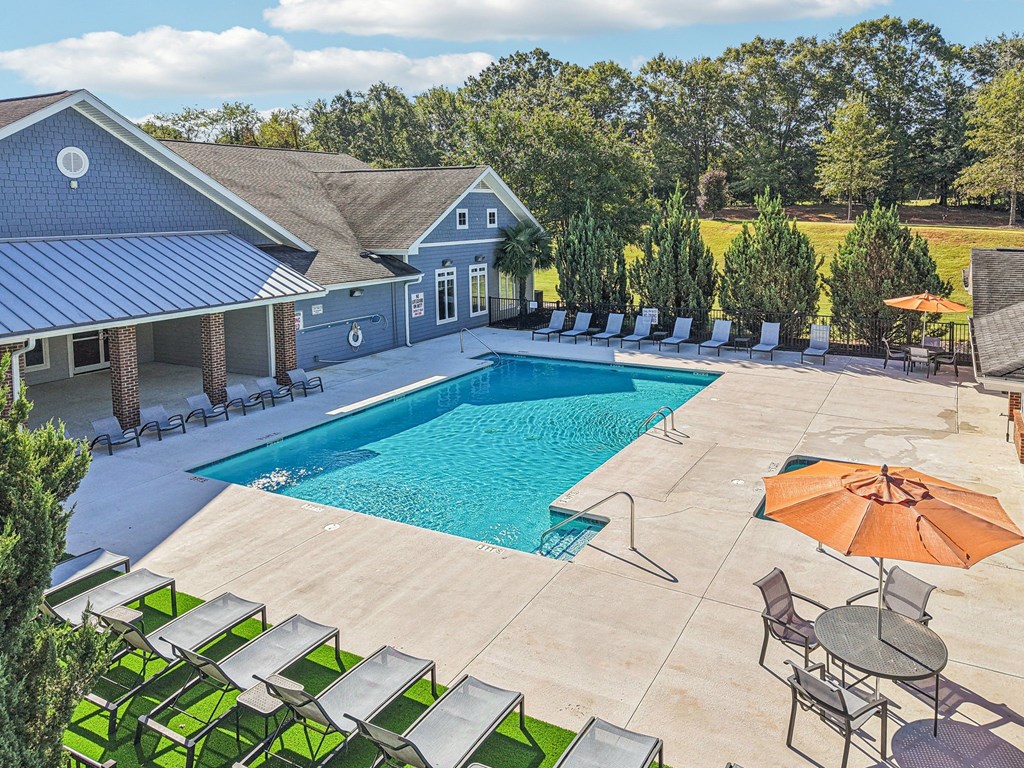 A large outdoor swimming pool surrounded by lounge chairs and umbrellas.