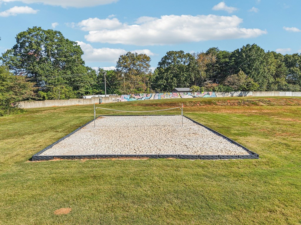 A large sand pit in the middle of a grassy field.