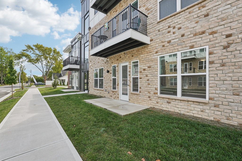 A brick building with a balcony and a walkway in front.