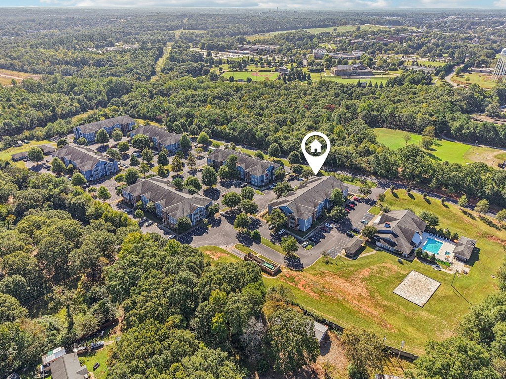 A bird's eye view of a residential area with a swimming pool and trees.