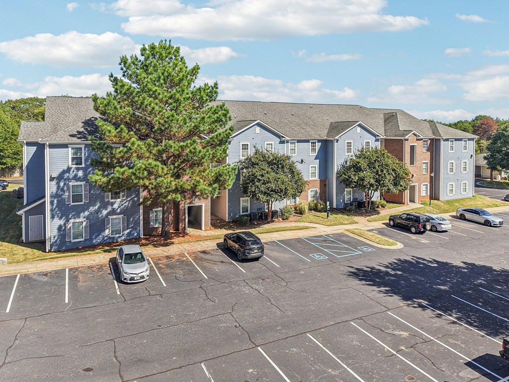 A parking lot with cars and apartment buildings in the background.