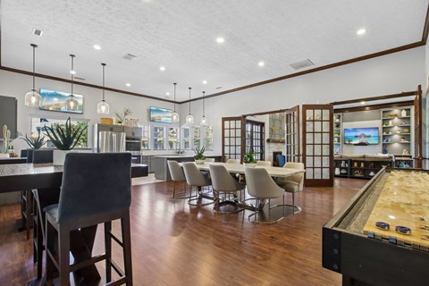 A billiard table is in the foreground of a room with a pool table and a bar.