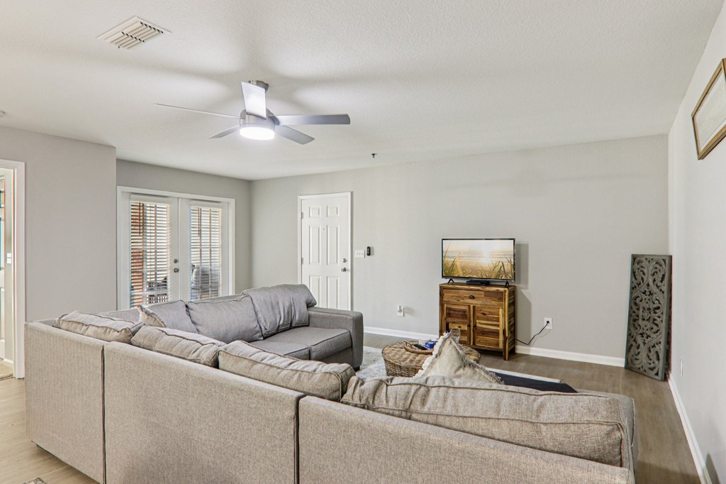 A living room with a grey couch and a ceiling fan.